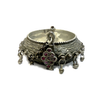 Antique Arabian silver hinged bangle with bell drops and garnet clasp, angled view